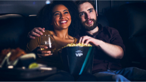 Couple dégustant des boissons et de la nourriture tout en regardant un film dans une salle de cinéma.